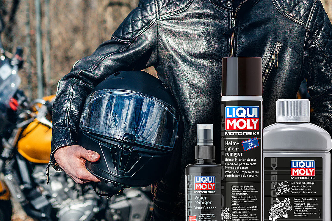 Motorradhelm im Hintergrund, im Vordergrund Motorbike Artikel: Visierreiniger, Helminnenreiniger und Lederkombipflege